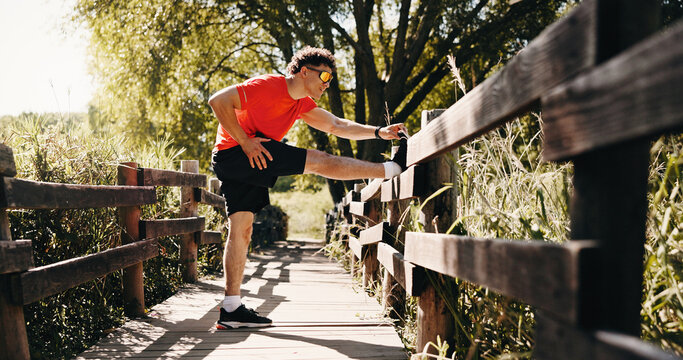 Legs, fitness and man in park stretching to start exercise, workout and training for cardio. Runner, athlete and person with warm up for endurance, mobility and wellness for active hobby outdoor