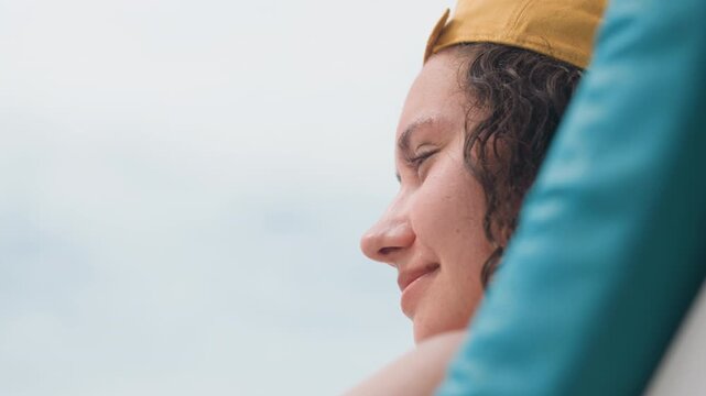 Calm woman relaxing. Peaceful woman reclines by tranquil sea. Serene female rests peacefully near quiet ocean shore. Relaxed woman with golden headpiece enjoys calmness beside peaceful seaside