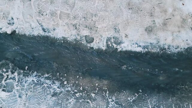 A running spring stream of melted, murky water