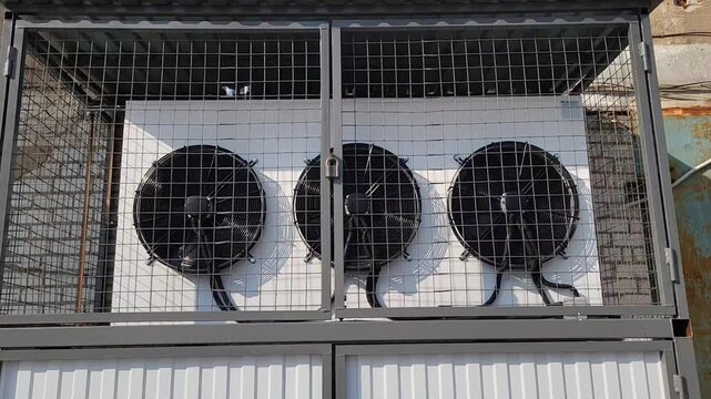 Fans working on the wall in a box behind a grate