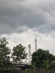 Obraz premium A BTS telecommunications tower in a green residential area against a cloudy sky