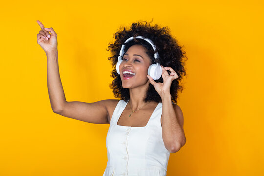smiling young woman isolated on background with headphones pointing