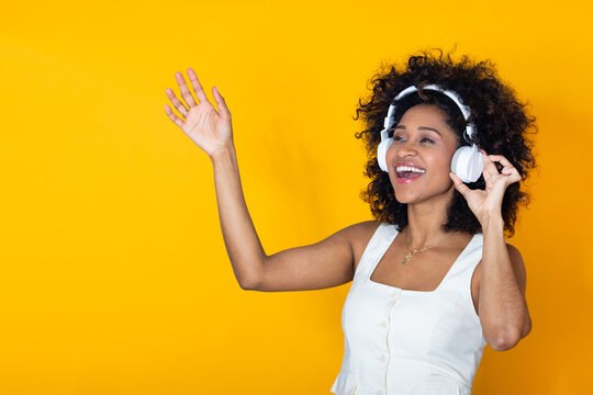 smiling young woman isolated on background with headphones pointing