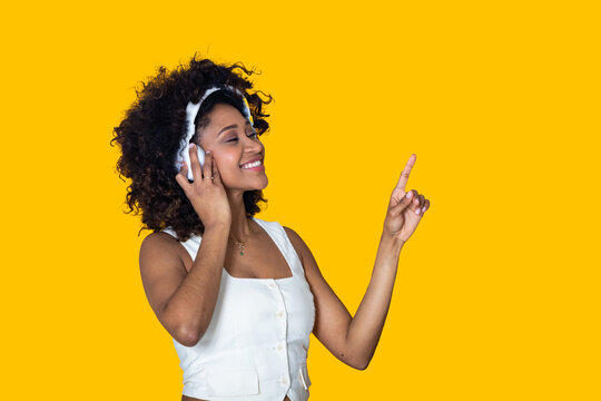 smiling young woman isolated on background with headphones pointing