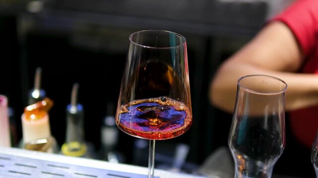 Bartender preparing Aperol sparkling wine cocktail mixing bar European nightlife drink beverage