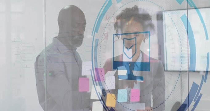 Man gesturing sticky note while woman holding note in office, showing digital security UI overlays