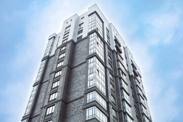 Fototapeta premium Modern high-rise building stands tall against clear blue sky. Steel and glass facade reflects sunlight with sharp precision. Architecture blends sleek lines with textured stone accents