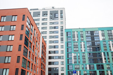 Fototapeta premium Modern apartment blocks stand tall and close. Bright colors contrast against grey skies. Windows reflect sunlight and city life. Urban development shapes cityscapes. Ideal for real estate