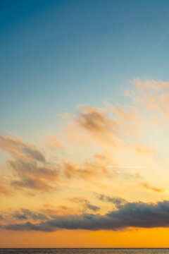 changing weather forecast. air pressure. scenic cloudscape. golden clouds on the blue morning sky over sea horizon. idyllic sunrise vertical background. fantastic golden hour wallpaper at the sea