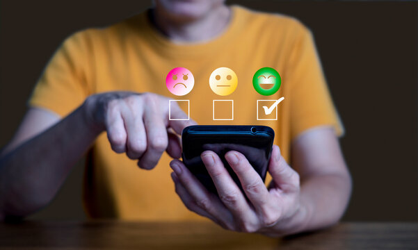 A woman holding a smartphone and pointing at it while floating emotion and checkmark icons appear above the screen, representing customer feedback, satisfaction ratings, online reviews.