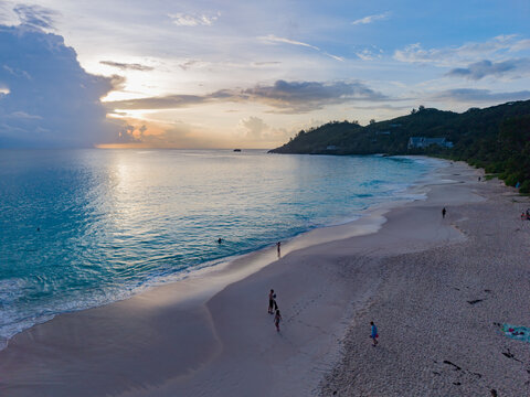 Aerial view of a serene beach with turquoise waters meeting the soft, sandy shore under a pastel sky, Quatre Bornes, Mahe Island, Seychelles.