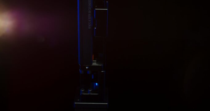 Industrial metallic machine component with serial number and blue light accent in a dark studio