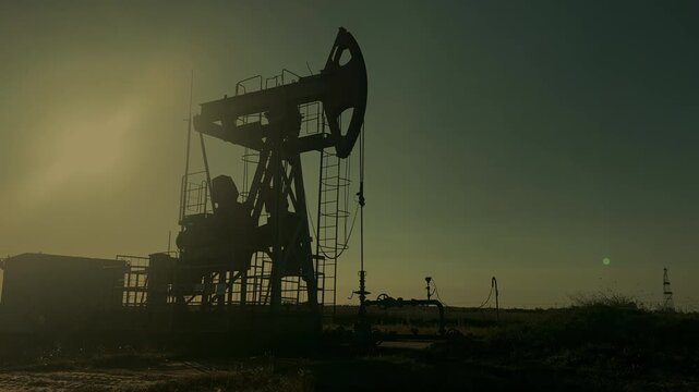 Extraction of petroleum. Oil Pump Jack in motion on Sunrise at Oil Field. Petrolium crude Industrial. Crude pump jack on morning sunrise. Extraction of petroleum in oilfield. Crude petroleum industry.
