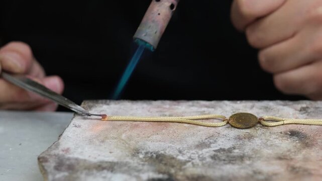 A goldsmith performs precision soldering on a gold chain bracelet using a gas flame. This stage connects fine components and forms the final structure in the jewelry manufacturing process.