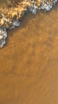 Waves on sand beach background, top view. Sea waves on tropical sand beach. Beach waves texture, background. Tropical ocean sunset. Tropical beach ocean water, top view. Seascape vacation resort. 