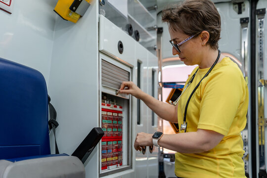 Paramedic taking medicine from ambulance storage compartment