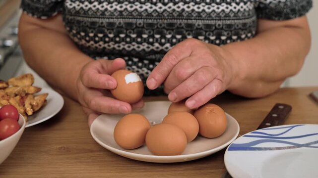 Peeling boiled egg for preparing Caesar salad. Removing shell from cooked egg for making Caesar salad. Cracking egg shell for salad preparation