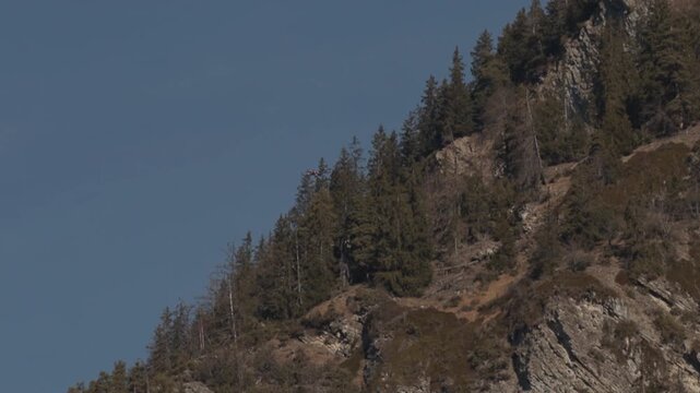 Wingsuit BASE jumper flying over Verbier surrounded by alpine mountains with snow-covered peaks. High-speed flight, dramatic scenery, and cinematic extreme sports action in the Swiss Alps.