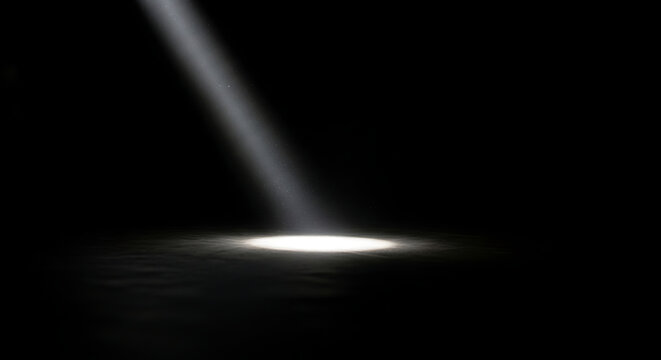 A bright spotlight shines in a dark room with a single beam of light