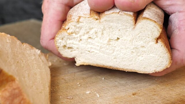 Baker hands squeeze and release loaf of soft white bread showing product quality. High quality fresh wheat bread from premium flour and yeast. Bread production and bakery business. harm of flour.