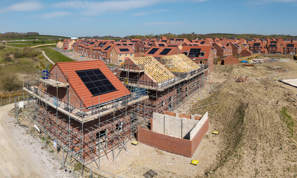 Aerial view of new build houses under construction with rooftop solar panels and exposed roof beams