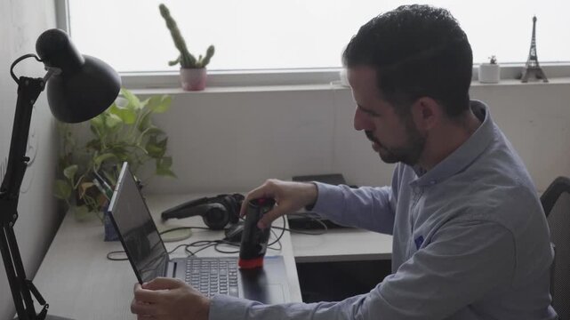 Man cleaning laptop keyboard with vacuum cleaner