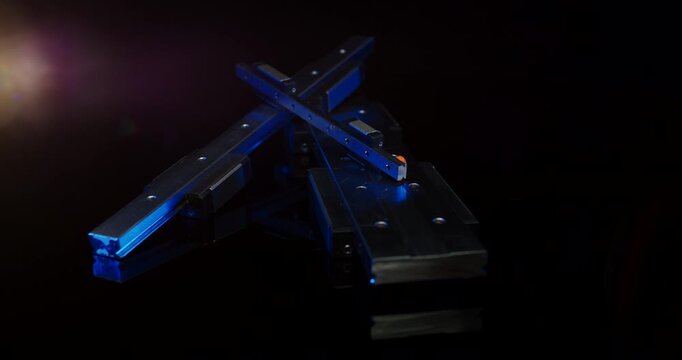 Group of industrial linear guide rails and carriage blocks with blue light in a dark studio