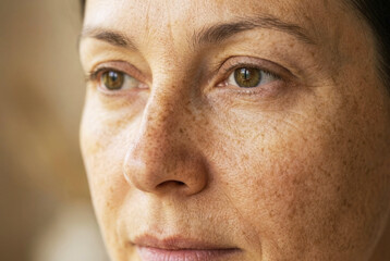 Fototapeta premium Macro detail of woman face showing skin texture freckles and hazel eye looking sideways