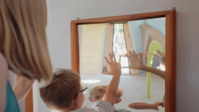 Children investigate bent glass reflections. Parents and kids enjoy warped mirror illusions together. Family members experiment with various altered and twisted mirror images as group