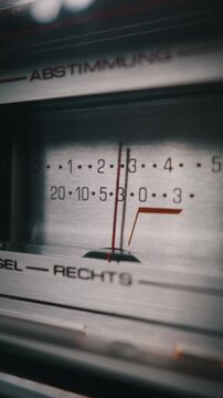 A vintage stereo receiver analog meter with a red needle fluctuating to measure audio signal strength. Concept of retro technology, precision engineering, and nostalgic sound mixing.