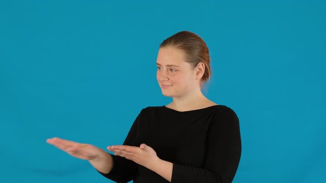 Woman exudes pathos and extends hands giving imaginary money in premise. Young female throws imaginary money into air on blue background