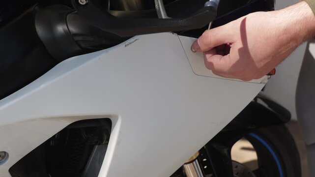 Closeup amateur mechanic unscrewing bolt from motorcycle fairing with socket wrench