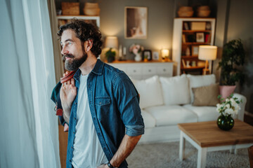 Bearded man contemplating future looking out window home