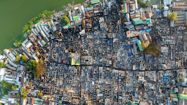 Aerial view of devastation after a fire, with scattered debris and remnants of homes, a stark contrast to the adjacent unaffected buildings, Dhaka, Dhaka Division, Bangladesh.