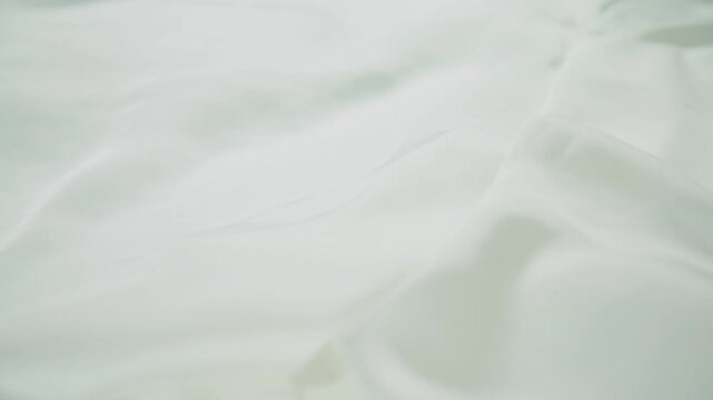 White fabric cloth falling in slow motion with soft flowing texture minimal background