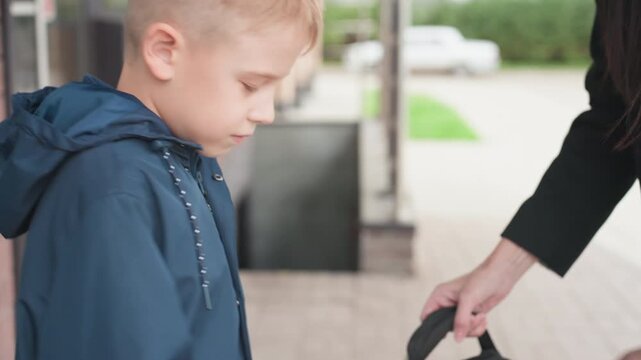 Mother helps her son get ready for school. Nurturing mother assists her son in preparing for school trip. Compassionate mother provides support to son in his early morning school preparations