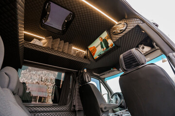 Naklejka premium Interior View of Luxury Camper Van with Custom Quilted Upholstery, Integrated Screen, and Ambient Lighting