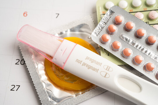 Pregnancy test and birth control pills on calendar, contraception health and medicine.