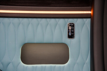 Naklejka premium Close up of light blue quilted leather car door panel with integrated usb charging ports and ambient lighting.