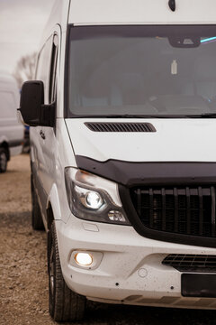 Front view of a white commercial delivery van parked on a dirt road during daylight.
