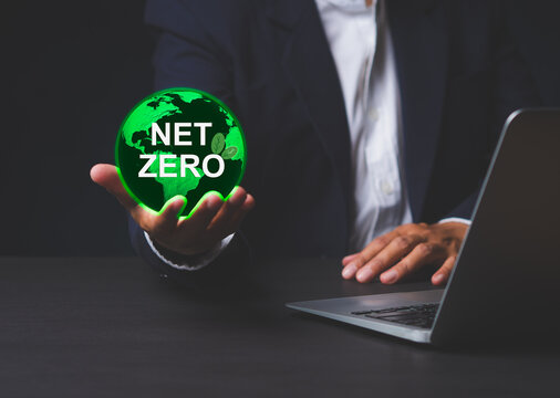Businessman holding net zero icon over laptop