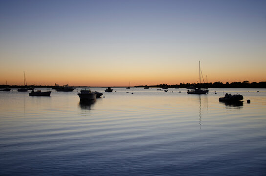 Boats on calm Polpis Harbor at sunset