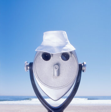White hat on coin-operated binoculars on beach
