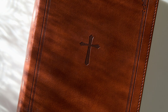 Closed Bible in sunlight on white background