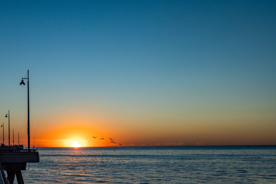 Sun setting above calm ocean and Venice Pier