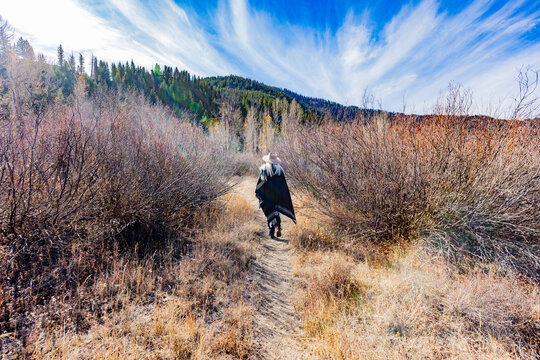 Rear view of woman in wool poncho on footpath in landscape