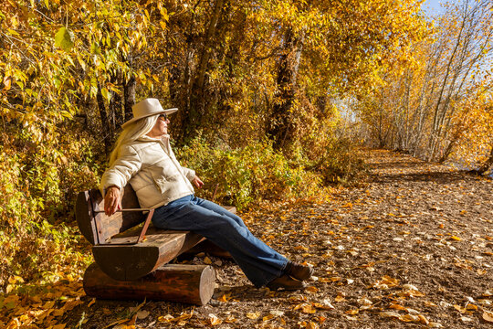 Senior woman relaxing on bench in landscape in autumn