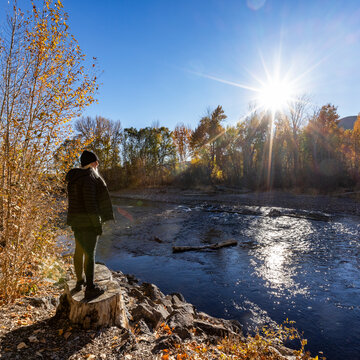 Woman facing Big Wood River on sunny autumn day