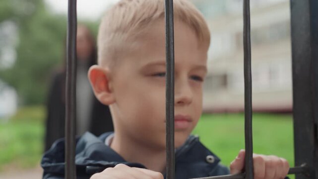 Child at entrance. Student poised at door. Young boy stands at school entrance. Pensive child positioned at gate awaiting education. Boy with serious look waits at school gate during morning hours
