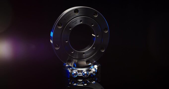 Precision industrial metal flange component and ball bearing with blue lighting in a dark studio